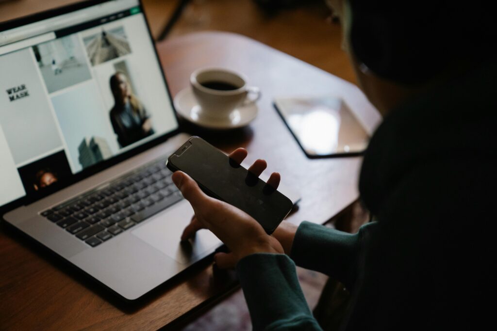 Man sitting indoors working on laptop and smartphone with coffee. High angle view.